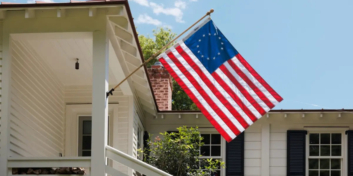 American flag placement for businesses and homes featuring a Betsy Ross flag mounted on a white house porch.