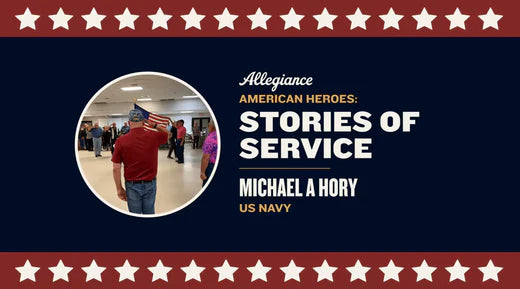 Michael A. Hory, a US Navy veteran, salutes while holding an American flag in a hall among other attendees