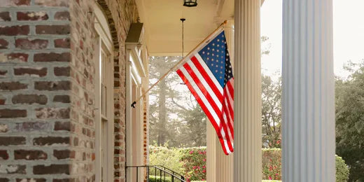 All-weather American flag mounted on a brick colonial-style porch, waving between elegant white columns