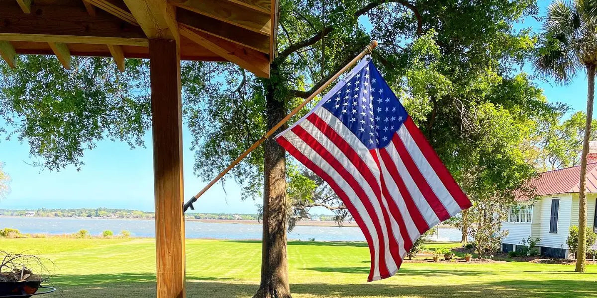  An American flag mounted on a wooden post waves in the breeze, highlighting proper flagpole maintenance for longevity.